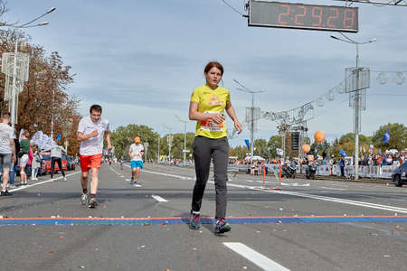 September 15, 2019 Minsk Belarus A tired woman crosses the finish line of a marathon ahead of an athlete catching up with herのeditorial素材