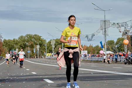 September 15, 2019 Minsk Belarus A young woman with a phone in her hand runs along the city road of the Minsk half marathonのeditorial素材