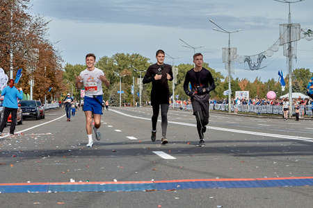 September 15, 2019 Minsk Belarus A marathon race in which three happy young participants run to the finish line on a city roadのeditorial素材