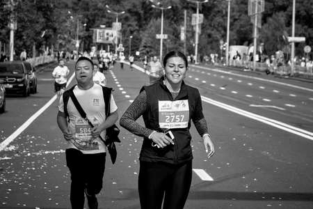 September 15, 2019 Minsk Belarus In black and white, this is a marathon race in which a happy man and woman run to the finish line on a city roadのeditorial素材