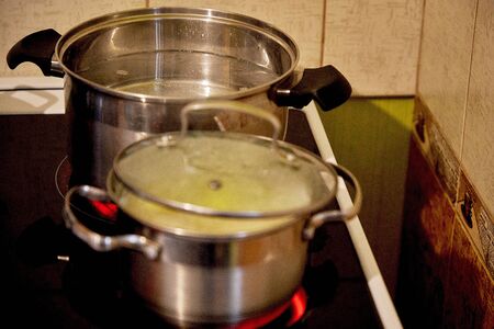 Two pots are on the stove, boiling water in a pot where potatoes are cookedの写真素材