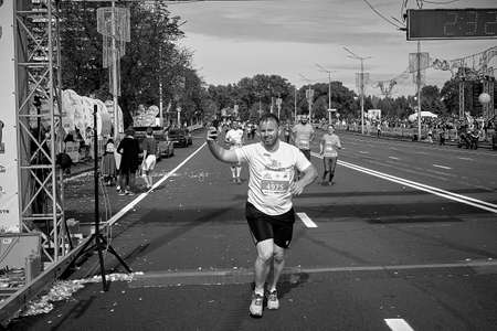 September 15, 2019 Minsk Belarus In black and white,a marathon race in which an active, happy participant crosses the finish line with his hand raisedのeditorial素材