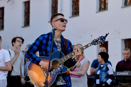 June 1, 2019 Minsk Belarus Close-up of a hipster musician with glasses, playing guitar, standing on the street in the eveningのeditorial素材