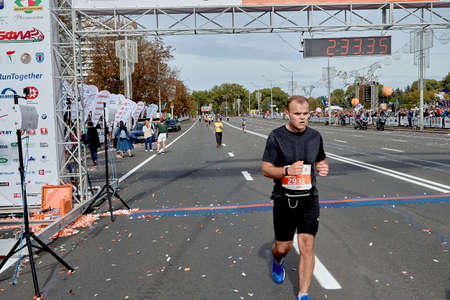 September 15, 2019 Minsk Belarus An athlete wearing headphones crossed the finish line of the marathon on a city roadのeditorial素材