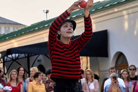 May 25, 2019 Minsk Belarus Girl actress in striped clothes shows theatrical performance with a red ball at the street.のeditorial素材