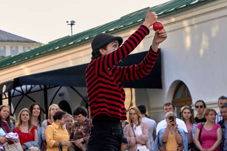 May 25, 2019 Minsk Belarus Girl actress in striped clothes shows theatrical performance with a red ball to the music at the street.のeditorial素材