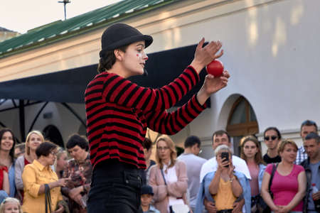 May 25, 2019 Minsk Belarus Close-up,girl actress in striped clothes shows theatrical performance with a red ball to the music at the street.のeditorial素材