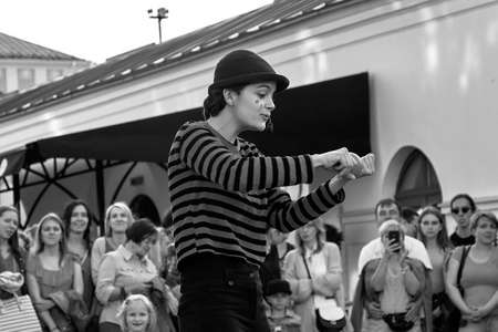 May 25, 2019 Minsk Belarus In black and white, girl actress in striped clothes shows theatrical performance with a red ball to the music at the street.のeditorial素材