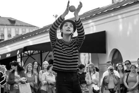 May 25, 2019 Minsk Belarus In black and white, girl actress in mime costume and makeup shows theatrical performance with a red ball to the music at the street.のeditorial素材