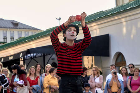 May 25, 2019 Minsk Belarus Girl actress in mime costume and makeup shows theatrical performance with a red ball to the music at the street.のeditorial素材