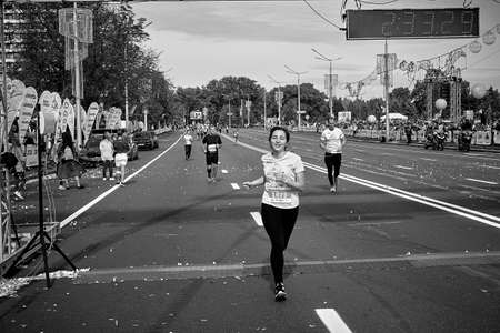 September 15, 2019 Minsk Belarus In the black and white image, a happy woman crosses the finish line on a city roadのeditorial素材
