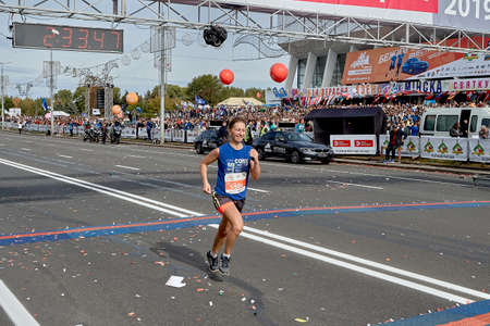September 15, 2019 Minsk Belarus An active smiling woman crosses the finish line of the marathonのeditorial素材