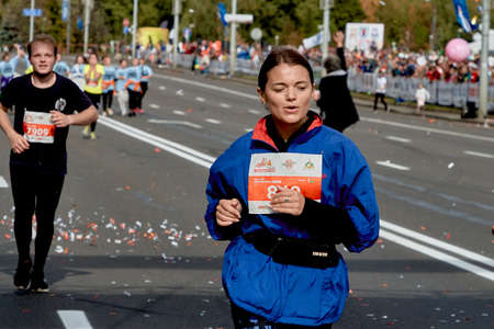 September 15, 2019 Minsk Belarus Close up of a young woman in a blue jacket running a marathonのeditorial素材