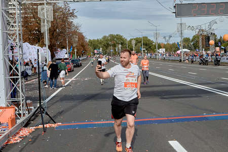 September 15, 2019 Minsk Belarus A marathon race in which an active participant crosses the finish line while looking at their smartphoneのeditorial素材