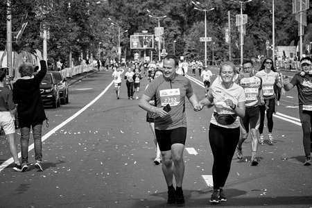 September 15, 2019 Minsk Belarus In the black-and-white image, a pair of happy marathon runners run hand in hand ahead of the participantsのeditorial素材