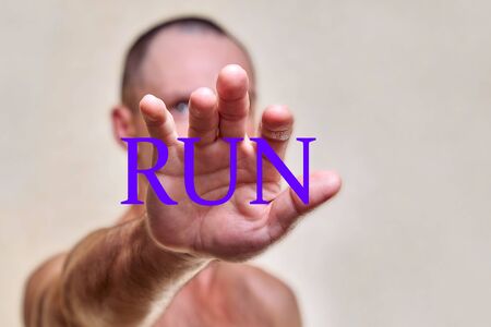 Scared man put his hands forward..On hand inscription run. Concept of a person calling for a runの写真素材