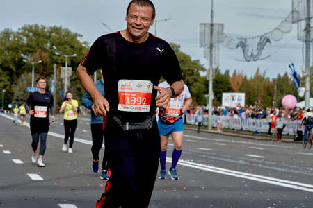 September 15, 2019 Minsk Belarus A marathon race in which a close-up of a happy Mature participant in glasses runs along the roadのeditorial素材