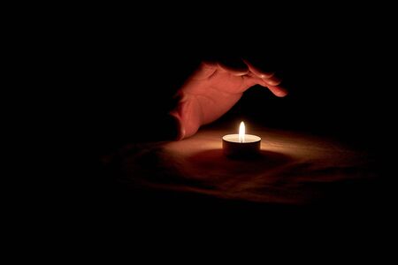 A human hand over a burning candle in honor of the commemorationの写真素材