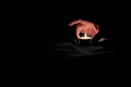 A human hand puts a burning candle on the table in honor of the commemorationの写真素材