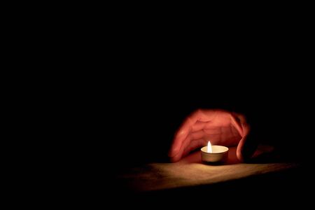 On memorial day a human hand stands next to a burning candleの写真素材
