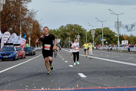 September 15, 2019 Minsk Belarus Minsk hosts a half-marathon, where a happy athlete with a phone in his hand runs to the finish lineのeditorial素材