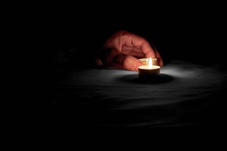 There is a memorial day on which a person puts a burning candle on the table next to a burning candleの写真素材