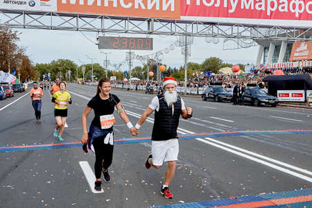 September 15, 2019 Minsk Belarus A marathon race in which a happy man with a white Santa Claus beard and a woman cross the finish line hand in handのeditorial素材