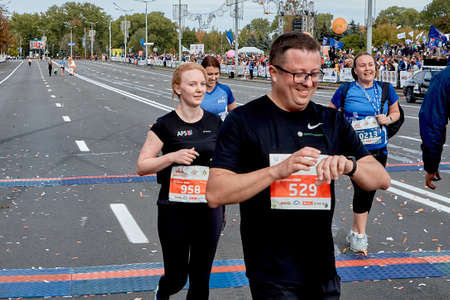 September 15, 2019 Minsk Belarus A marathon race in which close-ups of happy participants cross the finish line.The athlete looks at the smart watch on his hand that monitors his heart rateのeditorial素材