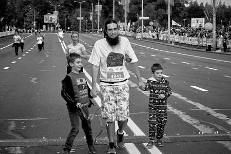 September 15, 2019 Minsk Belarus An athlete with a beard and two young sons crosses the finish line of a marathonのeditorial素材