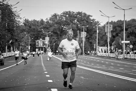 September 15, 2019 Minsk Belarus In black and white, a marathon race in which an elderly athlete runs to the finish lineのeditorial素材