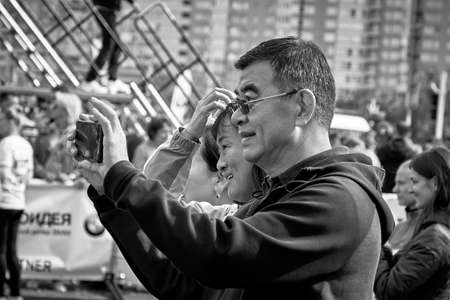 September 15, 2019 Minsk Belarus A man holds up his mobile phone to take a photo of the marathon in Minskのeditorial素材