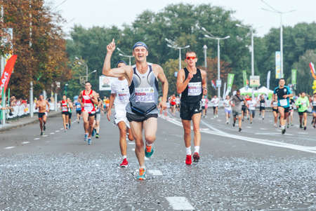 September 9, 2018 Minsk Belarus Half Marathon Minsk 2018 A marathon race in which a happy participant runs with his hand raised on a city road ahead of athletesのeditorial素材