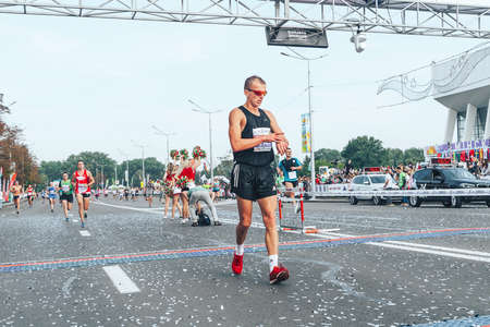 September 9, 2018 Minsk Belarus Half Marathon Minsk 2018 The contestant crosses the finish line looking at the smartwatch on his hand that monitors his heart rateのeditorial素材