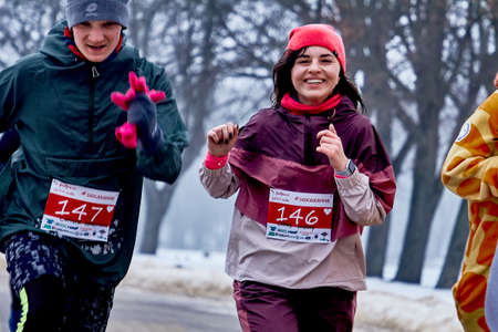 February 9, 2019 Minsk Belarus Run dedicated to February 14 Group of friends enjoying jogging in the park in winter Young slim girl running in the park in early winter.のeditorial素材