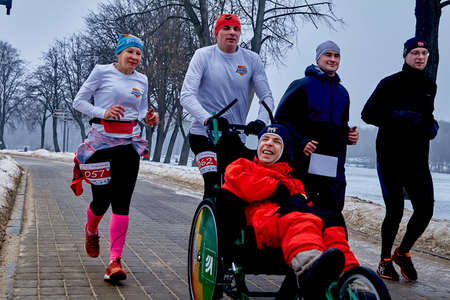 February 9, 2019 Minsk Belarus Run dedicated to February 14 For the Qahanna A crowd of athletes runs with a disabled person sitting in a wheelchair on the way to the Parkのeditorial素材