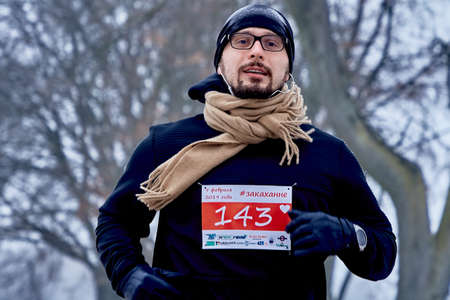 February 9, 2019 Minsk Belarus Run dedicated to February 14 Close-up of a man with glasses Running along a road in a Park in winterのeditorial素材