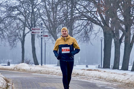 February 9, 2019 Minsk Belarus Run dedicated to February 14 Athlete runs along the road in the park in winter in the frostのeditorial素材