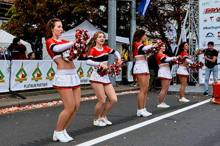 September 15, 2019 Minsk Belarus The photographer takes pictures at the start of the marathon, as a close-up of beautiful girls-dancers of support groups with large bows in their hands.のeditorial素材