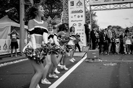 September 15, 2019 Minsk Belarus There is a close up of happy beautiful girls dancing next to athletes before the start of the marathon. Black and white imageのeditorial素材