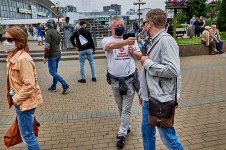 June 7 2020 Minsk Belarus Masked opposition blogger Nikolai Maslovsky is broadcasting live on the street using his phone and microphone asking the man questionsのeditorial素材