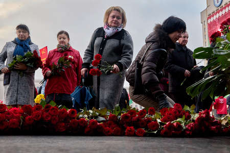 Elderly and not very participants in a communist opposition political gathering laing at flowers at the monument to Lenin. Anniversary of the 1917 revolution. November 7, 2019 Minsk Belarusのeditorial素材