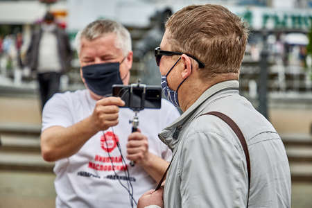 June 7 2020 Minsk Belarus A man answers a blogger's question with a phone and microphone in his handのeditorial素材