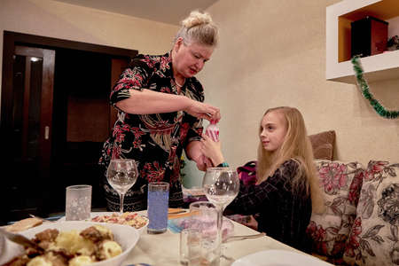 Birthday of a 12-year-old girl. Grandma gives her a gift at homeの写真素材