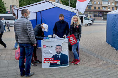 June 14 2020 Minsk Belarus A woman cast her votes for an opposition candidate next to a happy initiative groupのeditorial素材