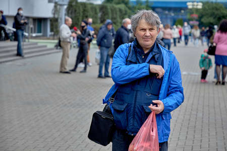 June 14 2020 Minsk Belarus A Mature man with a cellophane bag in his hand is walking down the streetのeditorial素材