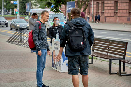 June 14 2020 Minsk Belarus Happy people talk next to the signature collection tableのeditorial素材