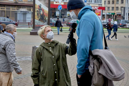 June 14 2020 Minsk Belarus Close up of a masked female reporter with a microphone talking to a tall masked man on the streetのeditorial素材
