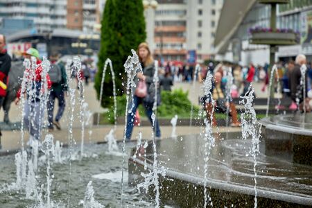 Fountain on the background of walking peopleの写真素材