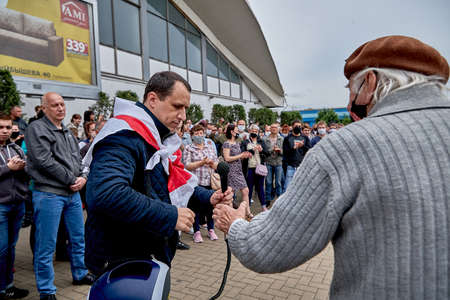 June 7 2020 Minsk Belarus Rally when the opposition leader wrapped in a flag gives a microphone to an elderly man in a maskのeditorial素材