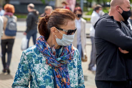May 24 2020 Minsk Belarus. Virus mask mature woman standing wearing face protection in prevention for coronavirus in Belarus. Lady walking on city streetのeditorial素材